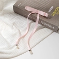 Dettaglio del fermaglio a fiocco in raso rosa con nastri lunghi e pendenti di perle - Rosa