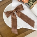Detail van koffiekleurige kantstrik met lange linten en golvende kanten randen - Tan