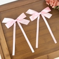 Lazos de satén rosa con cintas largas en una bandeja de madera con una decoración de rosa - Rosa