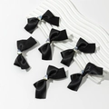 Vue détaillée de six barrettes à nœuds en satin noir avec un cœur en cristal étincelant - Noir