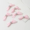 Set de 6 barrettes nœuds en satin rose avec cristal cœur sur un plateau à vagues blanc - Rose