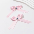 Detail van roze strik haarclips met hartvormige edelstenen op een witte achtergrond - Roze