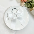 Detail eines eleganten weißen Satin-Haargummis mit Schleife und langen Bändern - Weiß