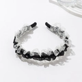Detalle de una elegante diadema de encaje en blanco y negro con bordados y pliegues - Negro