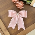 Pink satin bow hair clip with heart rhinestone on a vintage dark wood surface - Pink