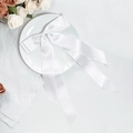 Detailansicht der weißen Satin-Haarschleife mit langen Bändern auf einem eleganten Teller - Weiß