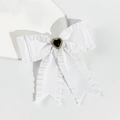 Detailed close-up of white ruffled ribbon bow hair clip with rhinestone heart centerpiece - White