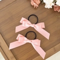 Pink satin bow hair ties with high elasticity black bands displayed on a wooden tray - Pink