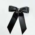 Close-up of black satin bow hair clip with a sparkling rhinestone heart crystal center - Black