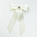 Close-up of cream white satin bow hairclip featuring a rhinestone heart gemstone - Beige