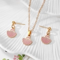 Detailed shot of gold shell jewelry set with pink enamel on a textured ceramic plate - Pink Shell Style (AN237)