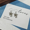 Vue détaillée des boucles d'oreilles papillon argentées avec strass brillants sur carte - Style Strass Double Couche (F)