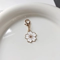 Makroaufnahme vom Kirschblütenanhänger mit weißem Emaille und goldenem Karabinerverschluss - Weiße Kirschblüte