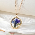 Détail du pendentif doré aux bords ondulés avec fleurs séchées bleues et mauves - Style Floral Bleu et Violet (D)