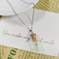 Vue macro d'un fantôme lumineux dans un pendentif mini bouteille en verre avec bouchon - Collier Vert