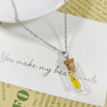 Gros plan d'un pendentif bouteille fantôme lumineux avec bouchon de liège sur chaîne argent - Collier Orange