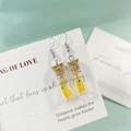 Vue détaillée des boucles d'oreilles bouteille en verre avec une figurine fantôme jaune - Boucles d'Oreilles Oranges