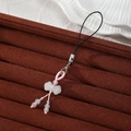 Detail of handmade woven phone charm featuring a white resin bow bead and colorful beads - White Bowknot Style (Style L)