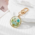 Preserved daisy and dried flower keychain with gold frame on white stone background - Blue Daisy Blue Flower White Gypsophila