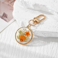 Detail view of handmade resin keychain with real dried flowers and a gold alloy lobster clasp - Orange Daisy Orange Flower White Gypsophila