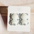 Boucles d'oreilles panda floquées en blanc et gris sur une carte de présentation - Panda en Colère