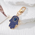 Detaillierte Ansicht des Hamsa-Schlüsselanhängers mit bösem Blick und Strasssteinen - Gold Blau Hamsa Hand