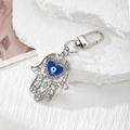 Makroaufnahme von Hamsa-Hand-Schlüsselanhänger mit blauem Auge und Kristall-Inlay - Silber Herz Auge