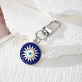 Makroaufnahme des blauen Evil-Eye-Anhängers mit Sonnenstrahl-Details am Schlüsselbund - Silber Sonne Rundes Auge