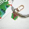 Dettaglio portachiavi a forma di regalo di Natale in oro con smalto rosso e verde - Regalo di Natale