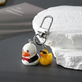 Nahaufnahme der Cartoon-Enten-Schlüsselanhänger aus Harz mit Metallverschluss auf dunklem Grund - Frackente