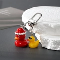 Makroaufnahme von Enten-Anhängern aus Harz mit Weihnachtsmütze und Sonnenbrille - Weihnachtstier