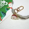 Vue détaillée d'un porte-clés Père Noël en émail rouge sur un socle en pierre blanche - Père Noël