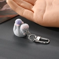 Détail d'un porte-clés hippopotame floqué gris tenu à la main pour l'échelle de taille - Gris Avec Balle Violette