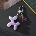 Close-up of a purple flocked balloon dog keychain with a pink glittery mini charm - Luminous Purple