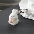 Close-up of white flocked rabbit keychain with orange carrot and silver D-ring - Winking Bunny
