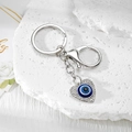 Detail of silver heart evil eye keychain with sparkling rhinestones on stone background - Silver Heart