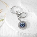 Polierter Evil Eye Schlüsselanhänger mit blauem Kern und funkelnden Strasssteinen auf Stein - Silber Großes Rundes Auge (1)