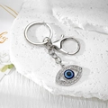 Close-up of silver evil eye keychain with sparkling rhinestones on white marble background - Silver Hollow Oblique Eye