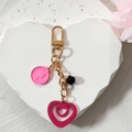 Detalle de colgante de moneda rosa con relieve y llavero dorado de doble corazón para bolsos - Corazón Rosa Fucsia