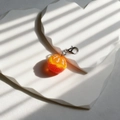 Mini resin orange fruit keychain with silver lobster clasp on white heart-shaped stands - Peeled Orange