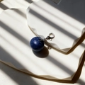 Deep blue spherical resin keychain with silver lobster clasp on a white geometric board - Blueberry