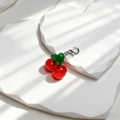 Detailansicht des realistischen roten Kirsch-Anhängers mit grünem Blatt und Silberverschluss - Kleine Kirsche