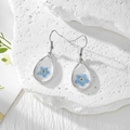 Boucles d'oreilles goutte en résine avec fleurs séchées bleues sur décor pierre - Une Seule Fleur Bleue