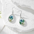 Macro shot of teardrop earrings featuring real blue and white dried flowers in resin - Dark Blue and White Flower