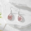 Détail des boucles d'oreilles gouttes en résine avec de vraies fleurs séchées roses - Gypsophile Rose