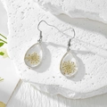 Détail de boucles d'oreilles goutte en résine avec fleurs séchées sur une base de pierre - Gypsophile Blanc