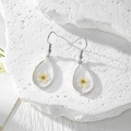 Vue détaillée de boucles d'oreilles en argent avec fleurs séchées jaunes en résine - Une Seule Fleur Blanche