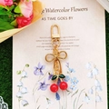 Red cherry keychain with gold bow and green leaf detail on floral decorative card - Solid Red Cherry