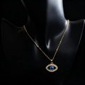 Golden Evil Eye necklace with blue bead and sparkling rhinestones on black display - Lace Gold Hollow Slanted Eye