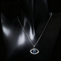 Detailed close-up of a silver Evil Eye pendant with blue stone on a black mannequin - Medium Silver Hollow Slanted Eye